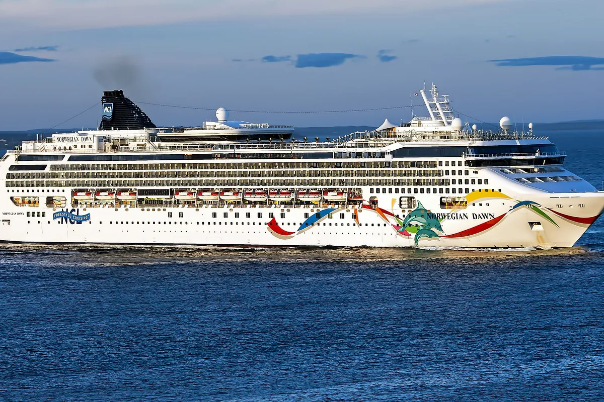 A large cruise ship, the Norwegian Dawn, sailing across a blue ocean